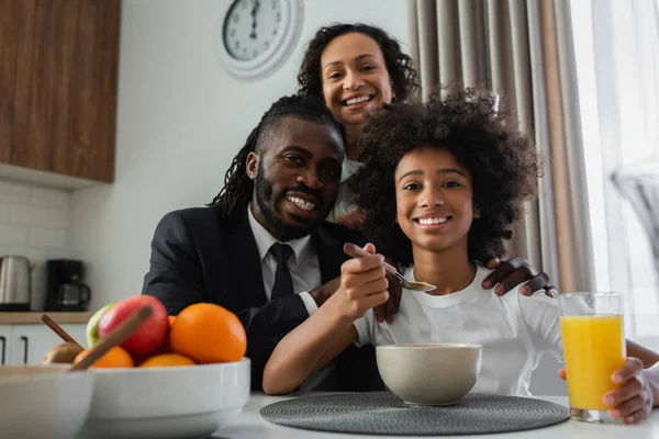 Família afro-americana feliz olhando para a câmera durante o café da manhã em casa — Fotografia de Stock