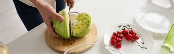 Vista superior del hombre recortado cortando lechuga cerca de ramas con tomates cherry maduros, pancarta - foto de stock