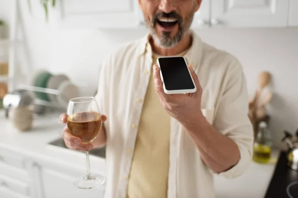 Vue recadrée de l'homme flou avec verre de vin blanc envoi message vocal sur téléphone portable avec écran blanc — Photo de stock