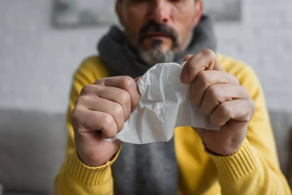 Selective focus of crumpled paper napkin in hands of cropped diseased man on blurred background — Stock Photo