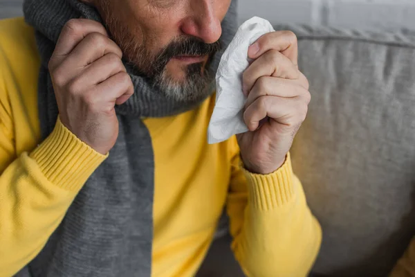 Частичный вид больного человека в теплом шарфе с бумажной салфеткой — стоковое фото