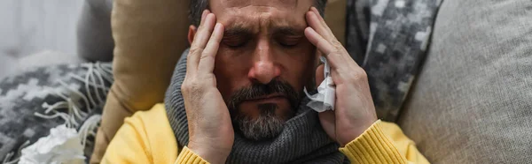 Vue de dessus de l'homme malade avec fermé couché sur le canapé et touchant la tête tout en souffrant de maux de tête, bannière — Photo de stock