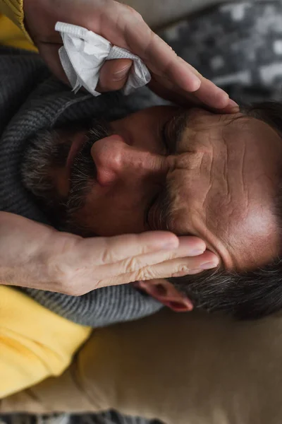 Vista superior del hombre enfermo con los ojos cerrados sufriendo de migraña y tocando la cabeza - foto de stock