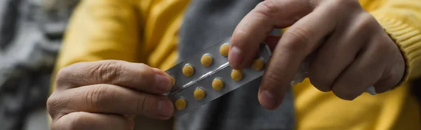 Cropped view of diseased man holding pills on blurred background, banner — Stock Photo