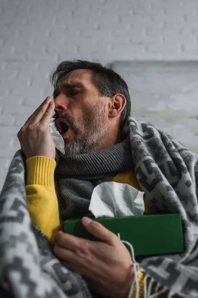 Vista a basso angolo dell'uomo che copre la bocca con la mano mentre tossisce e tiene in mano confezione di tovaglioli di carta — Foto stock
