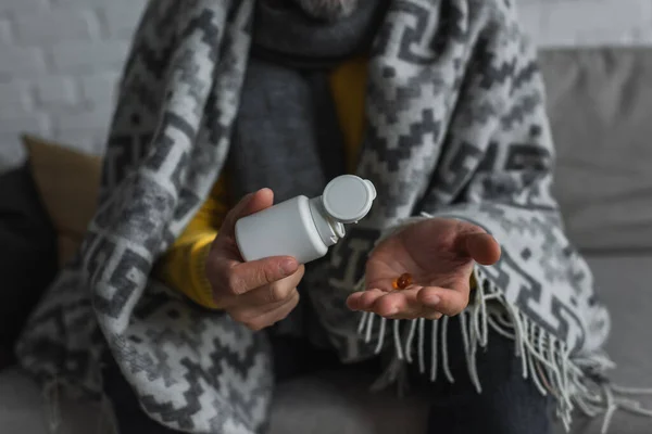 Vue recadrée de l'homme malade sous couverture chaude contenant et pilule — Photo de stock