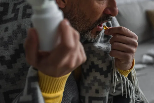 Cropped view of sick man taking pill while holding container on blurred foreground — Stock Photo