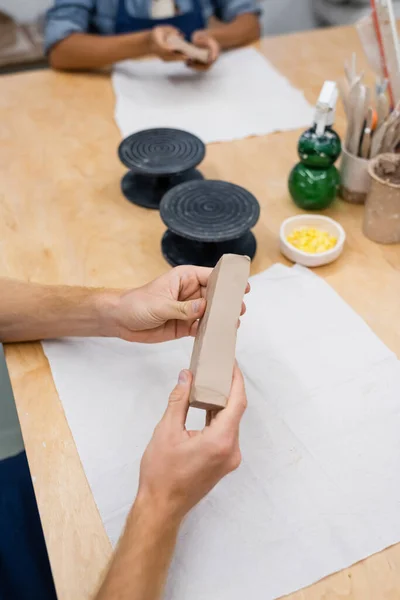 Cropped view of man shaping clay piece near african american woman — Stock Photo