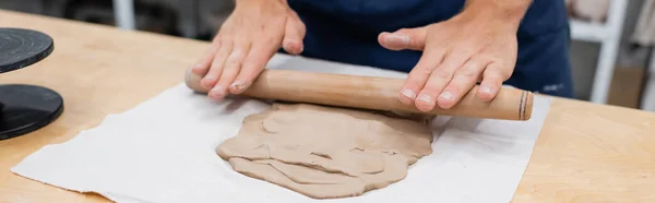 Vista cortada do homem no avental moldando peça de argila com rolo de pino durante a classe de cerâmica, banner — Stock Photo