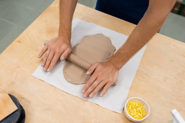 Vue du dessus de la pièce d'argile de modélisation homme avec rouleau à pâtisserie pendant la classe de poterie — Photo de stock