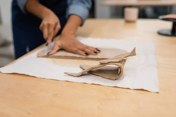 Pezzi affettati di argilla vicino ritagliato donna afro-americana artigianale durante la classe di ceramica — Foto stock