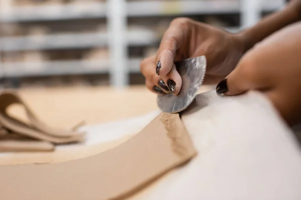 Cropped view of african american woman holding steel scraper while modeling clay piece — Stock Photo