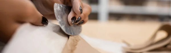 Cropped view of african american woman holding steel scraper while modeling clay piece, banner — Stock Photo