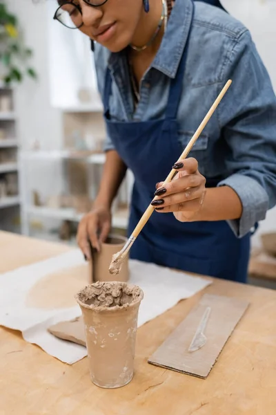 Cropped view of african american woman in eyeglasses holding clay shaper — Stock Photo