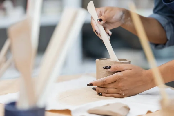 Visão parcial mulher afro-americana com manicure modelagem copo de barro com shaper durante a aula de cerâmica — Fotografia de Stock