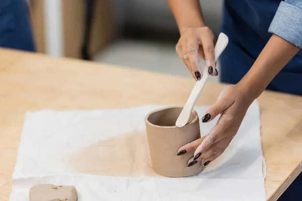 Vista parcial mujer afroamericana con manicura modelado taza de arcilla con formador durante la clase de cerámica - foto de stock