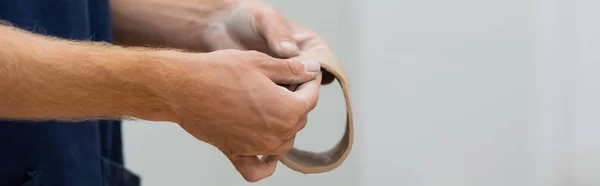 Vista ritagliata di uomo modellare pezzo di argilla in cerchio in mano durante la classe ceramica, banner — Foto stock