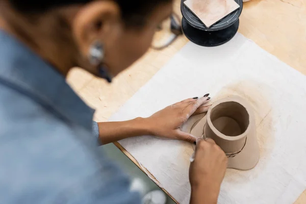 Vue du dessus de la femme afro-américaine façonnant tasse d'argile pendant le cours de poterie — Photo de stock