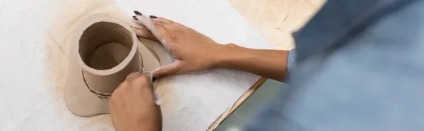 Vista dall'alto della donna afro-americana che modella la tazza di argilla durante la classe di ceramica, banner — Foto stock