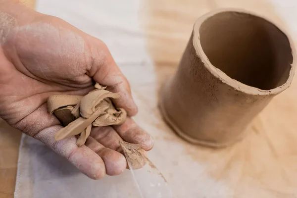 Обрізаний вид людини, що тримає нарізані шматки глини біля форми чашки — стокове фото