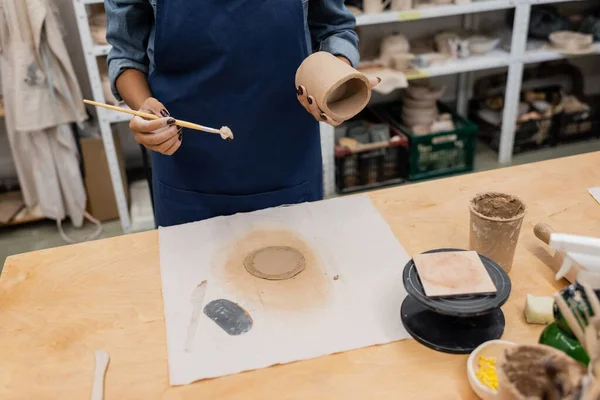 Cropped view of african american woman holding shaper and circle shape clay piece — Stock Photo