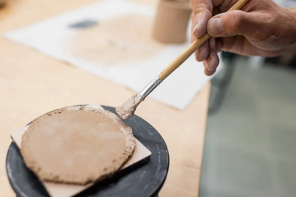 Close up view of man holding shaper in hand near flat clay piece — Stock Photo