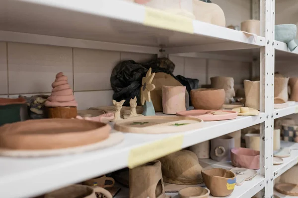 Diferentes esculturas de arcilla en los estantes de la tienda de cerámica - foto de stock