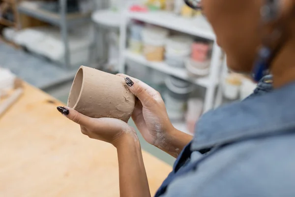 Vista parcial de la mujer afroamericana moldeando taza de arcilla en las manos - foto de stock