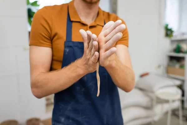 Обрезанный вид ремесленника, формирующего глину в мастерской керамики — стоковое фото