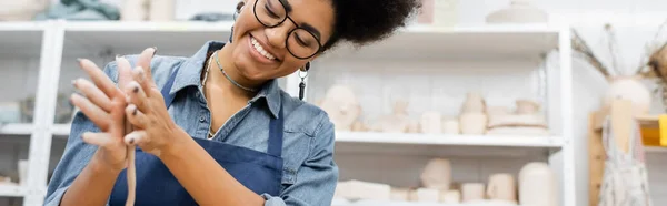 Positive afrikanisch-amerikanische Kunsthandwerkerin im Schürzenumformen von Ton in Werkstatt, Banner — Stockfoto