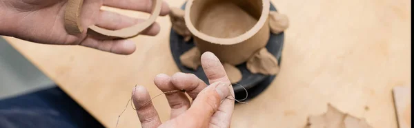 Top view of craftsman holding clay and fishing line in pottery workshop, banner — Stock Photo