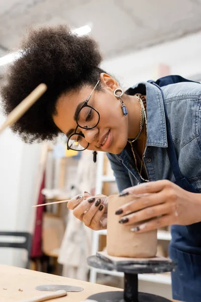 Artigiana afro-americana sorridente che fa scultura in argilla in studio di ceramica — Foto stock