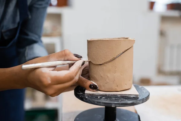 Cropped view of african american sculptor cutting clay in pottery workshop — Stock Photo