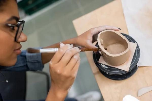 High angle view of african american sculptor making holes in clay product in workshop — Stock Photo