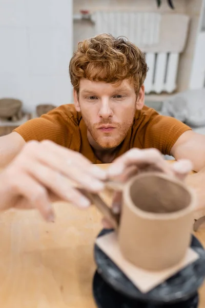 Pelirroja artesanal haciendo taza de arcilla borrosa en taller de cerámica - foto de stock