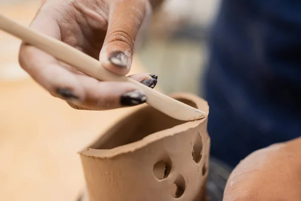 Close up view of african american craftswoman using tool while making clay product in workshop — Stock Photo