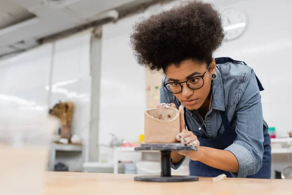 Africano americano artesão em óculos formando argila em oficina de cerâmica — Fotografia de Stock