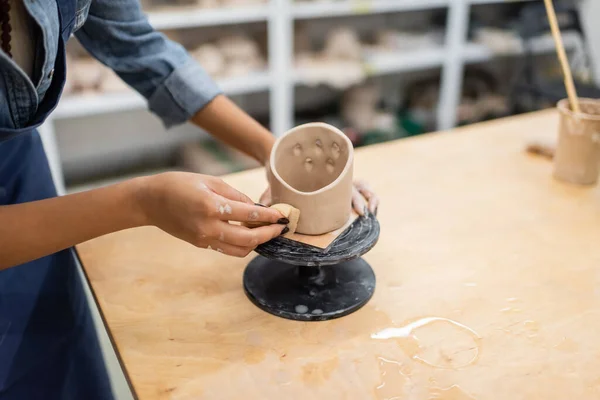 Vista recortada do artesão afro-americano formando escultura de argila com esponja em estúdio de cerâmica — Fotografia de Stock