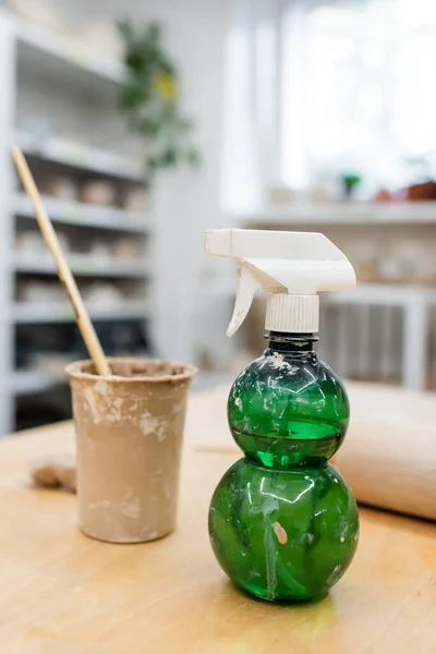 Water sprayer on table in blurred pottery studio — Stock Photo