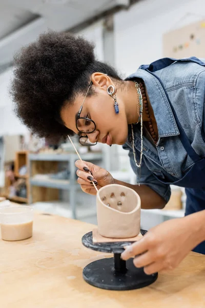 Young african american craftswoman forming clay with wooden stick in pottery workshop — Stock Photo