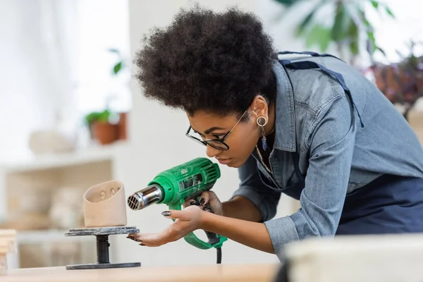 African american craftswoman in apron drying ceramic sculpture in workshop — Stock Photo