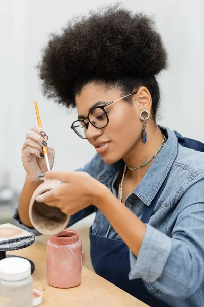 Jovem pintura artesanal afro-americana sobre produto cerâmico no estúdio de cerâmica — Fotografia de Stock