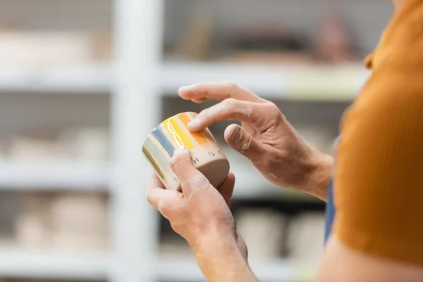 Vue recadrée de l'artisan tenant une tasse en céramique dans un atelier de poterie — Photo de stock