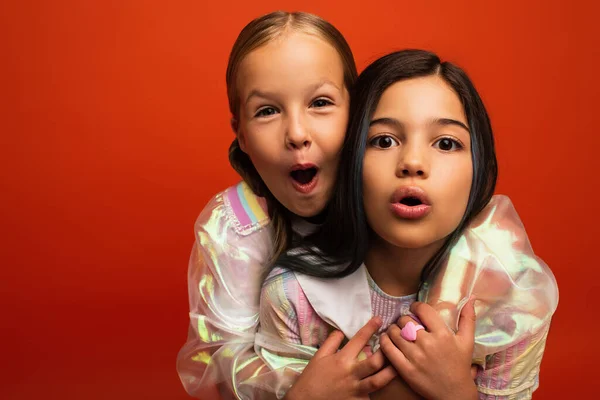 Lustige preteen Mädchen, die in die Kamera schauen und Grimassen mit offenen Mündern auf orange isoliert — Stockfoto