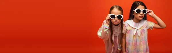 Preteen filles en robe et veste de pluie réglage des lunettes de soleil isolées sur orange, bannière — Photo de stock