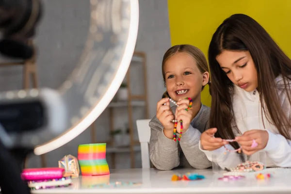 Preteen video bloggers with beaded bracelets near circle lamp on blurred foreground — Stock Photo