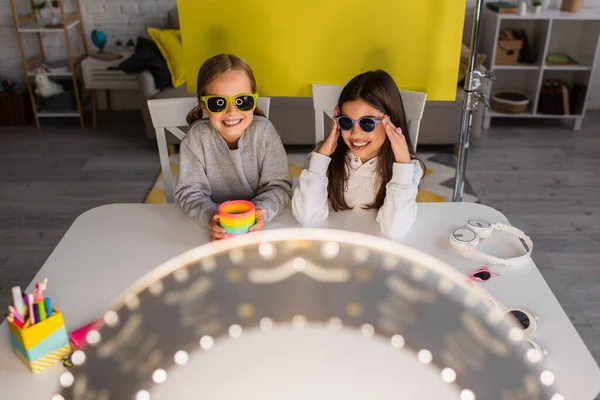 Vista de ángulo alto de video bloggers en gafas de sol de moda frente a la luz borrosa del anillo - foto de stock