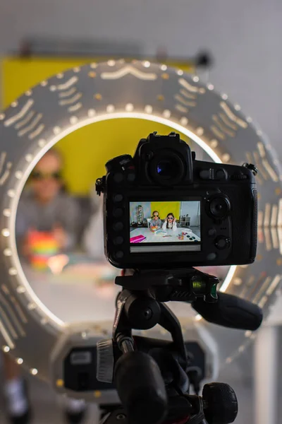 Selective focus of video camera in circle lamp with preteen bloggers in trendy sunglasses on screen — Stock Photo