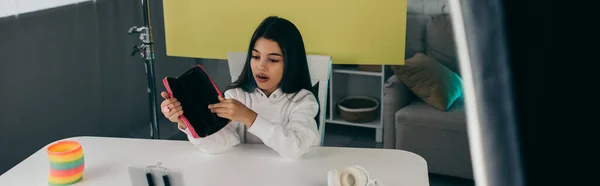 Morena chica mostrando estuche de lápiz mientras que la grabación de vídeo blog cerca de fondo amarillo en casa, pancarta - foto de stock