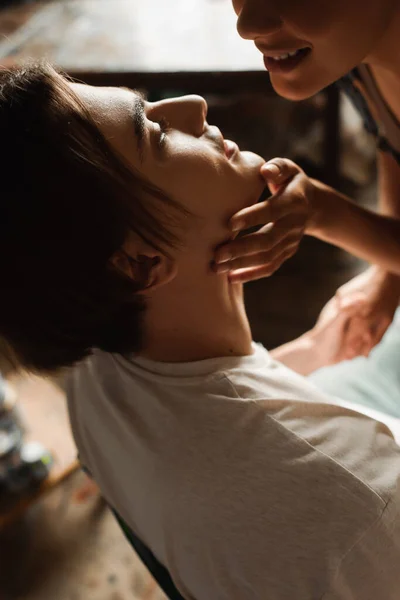 Smiling and sensual african american woman touching face of young artist in workshop — Stock Photo